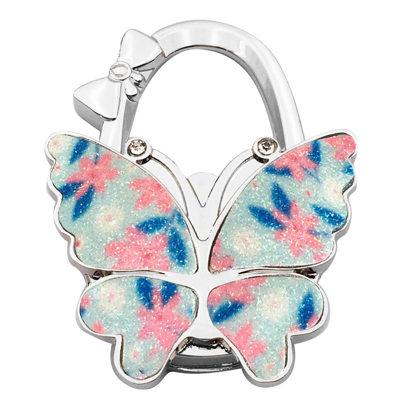 🦋👜【Compra uno y llévate otro gratis】Gancho plegable para bolso con forma de mariposa colorida